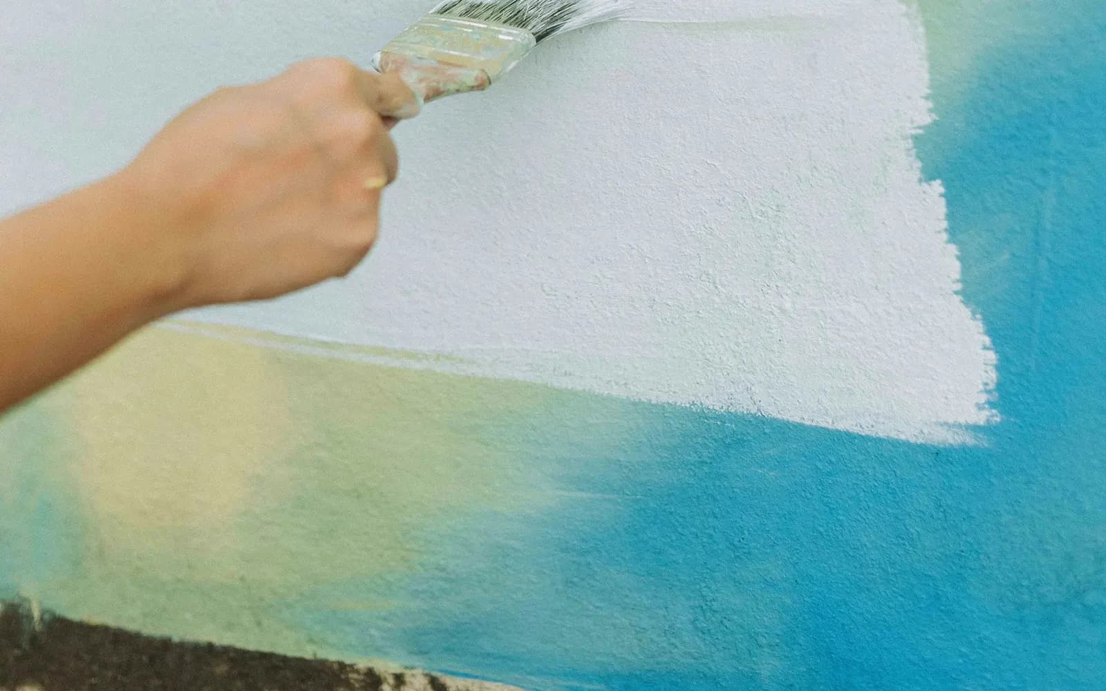 Person painting a white wall with a roller.