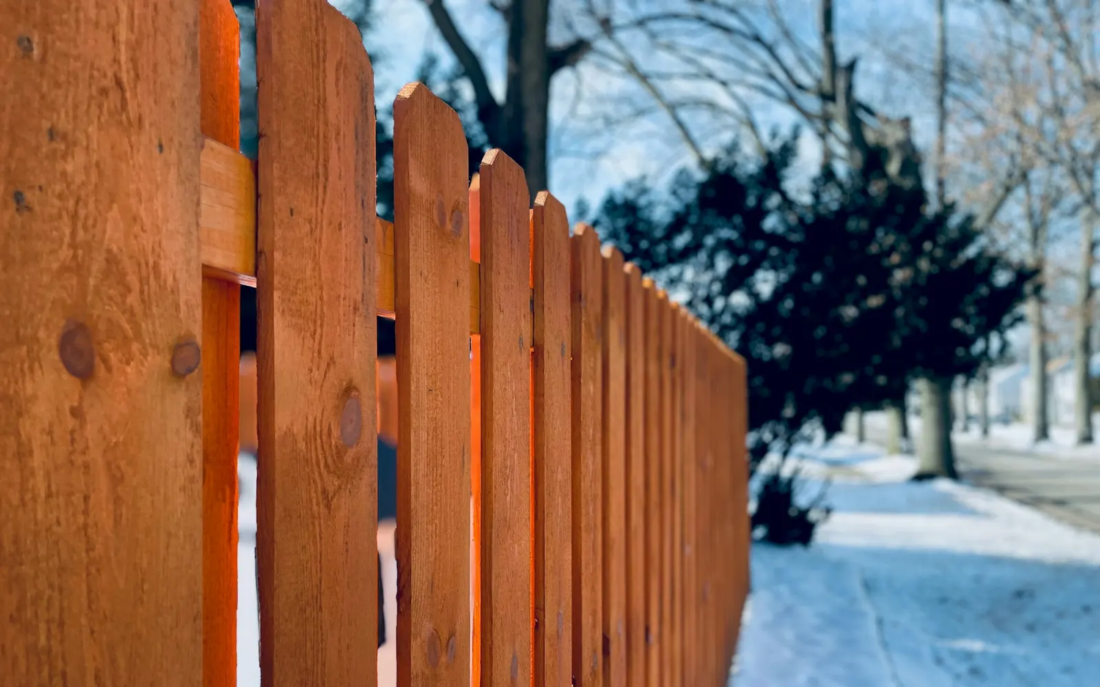 Close view of a wood privacy fence along a residential sidewalk.